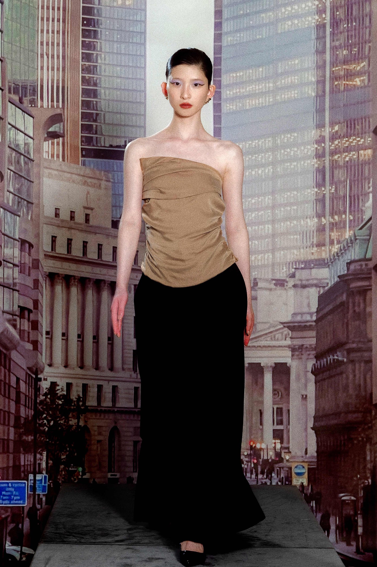 Woman in a beige top and black skirt standing in front of a cityscape