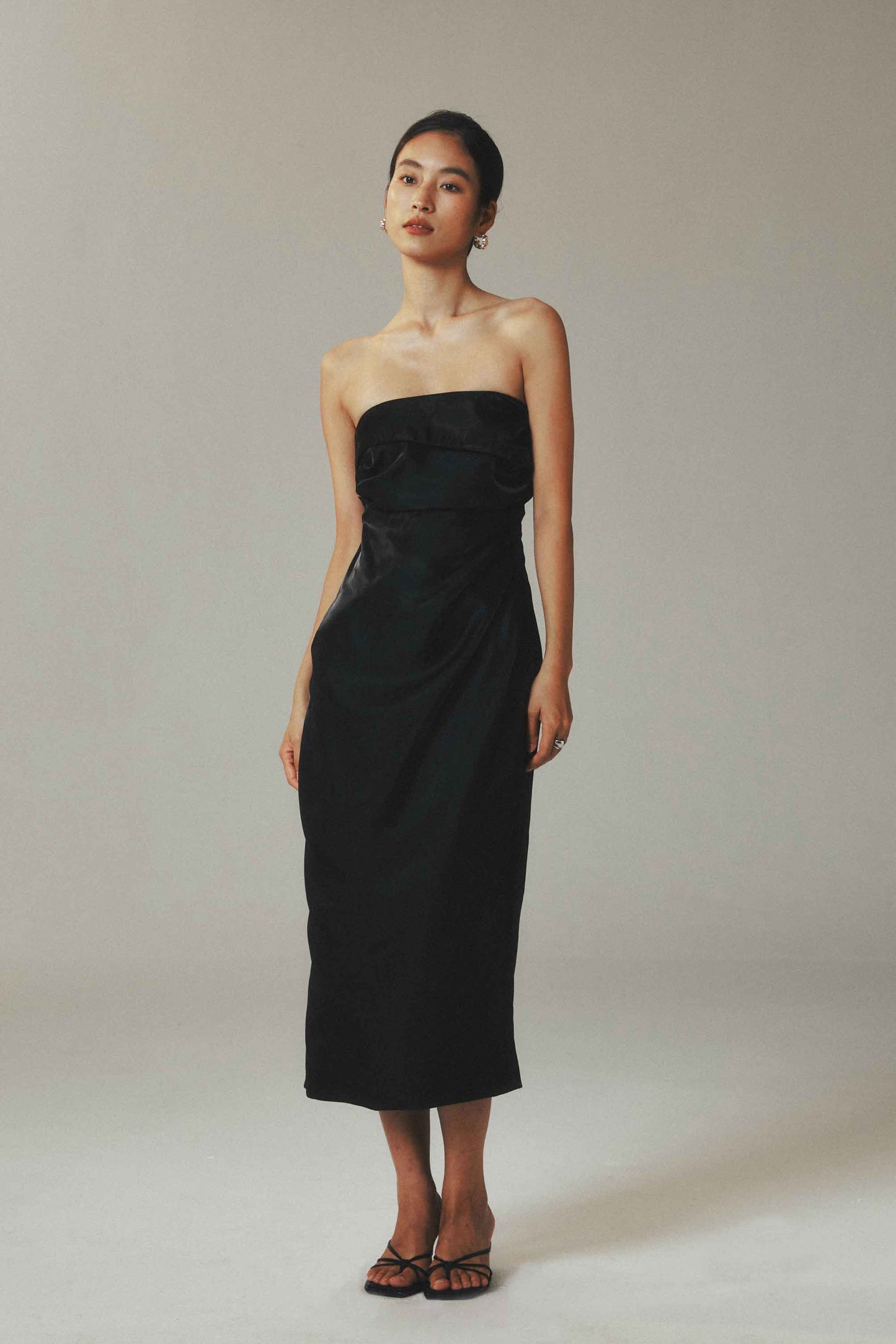 Model wearing black satin maxi sheath
dress with waist pleats