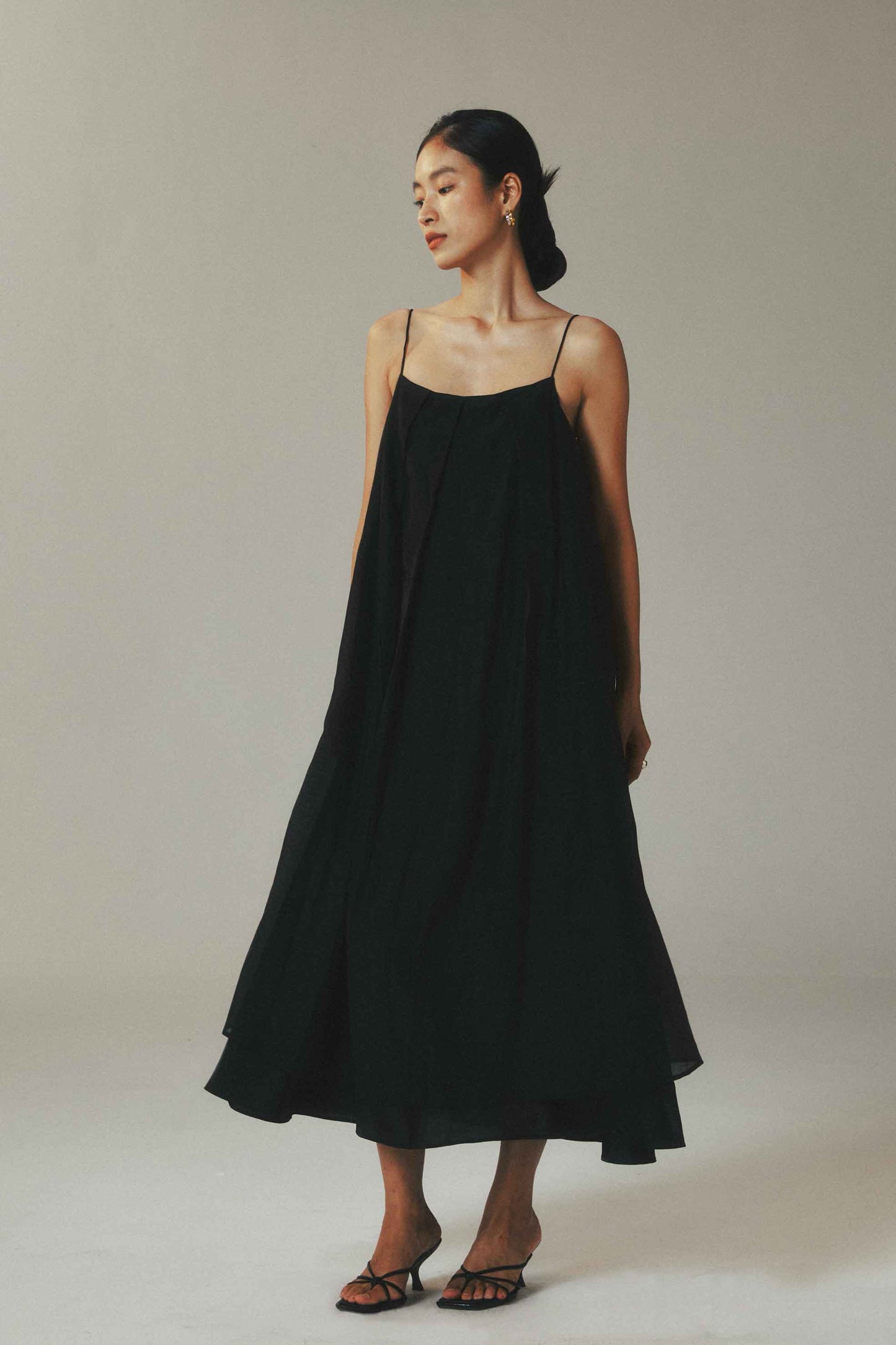 Woman wearing a black slip dress against a plain background