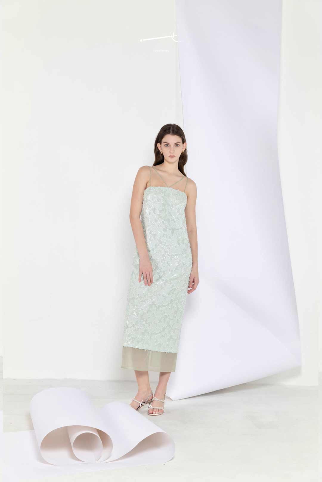 Woman wearing a light green strapless dress with a floral pattern on a white background