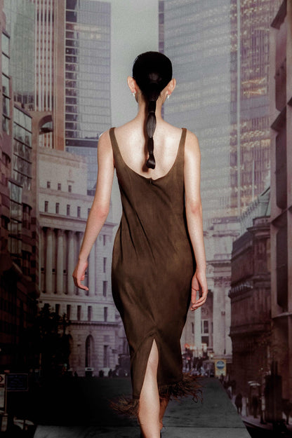 Woman in a brown dress walking away from the camera with a cityscape in the background