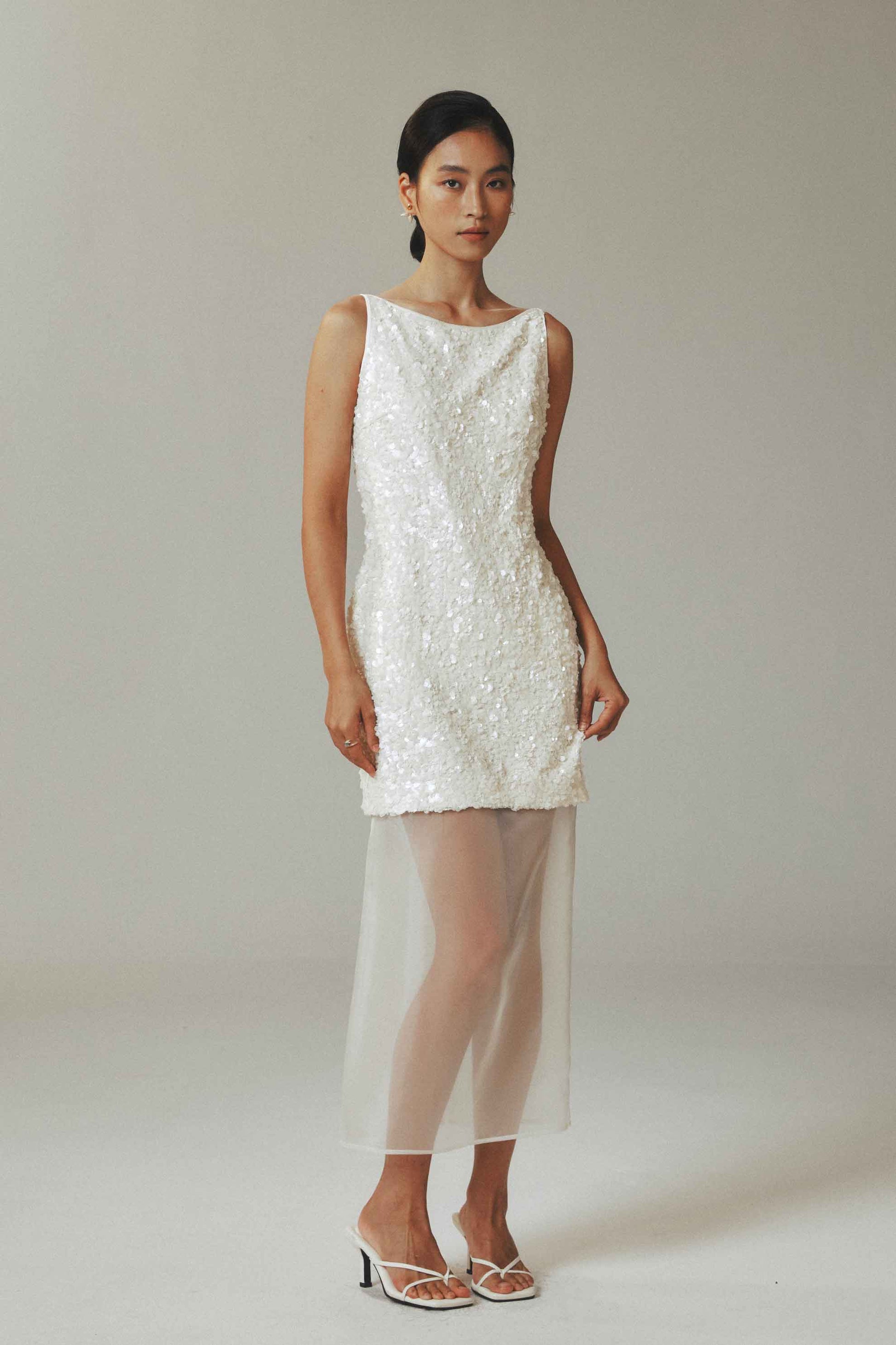 Model wearing white sequin mini dress with sheer tulle overlay