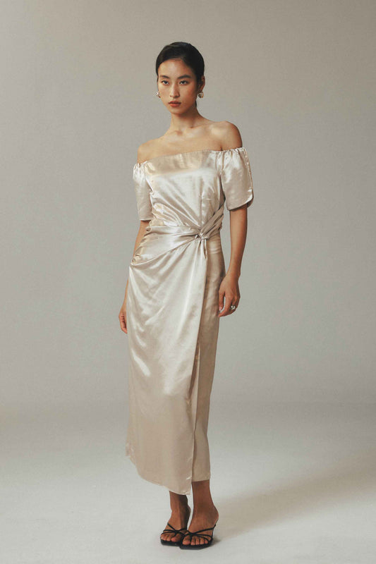 Model wearing off the shoulder maxi
dress in ice-silk fabric with button-pleated
detail