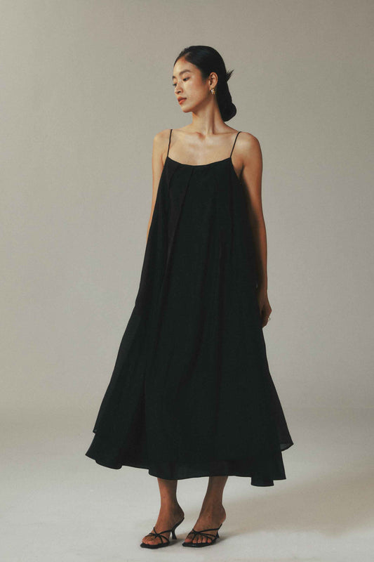 Woman wearing a black slip dress against a plain background